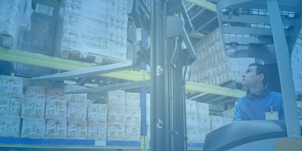 picture of a man operating a fork lift looking up at the products he is moving in a large warehouse